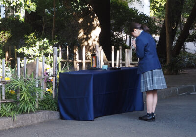 散華乙女の碑の前で手をあわせる高校生